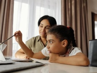 Mother and daughter engaged in online learning at home, using a laptop.